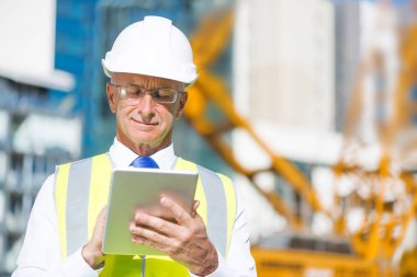 Kıdemli mühendis erkek takım elbise ve tablet PC'de çalışma kask