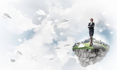 Mavi gök yeşil yüzen ada üzerinde duran zarif emin iş kadını