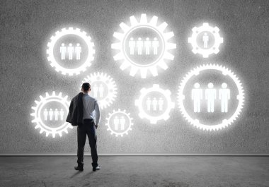 İş adamının çizilmiş dişli mekanizmasıyla duvara baktığı arka plan