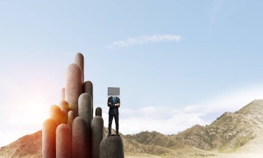 Arka plan üzerinde duran güzel gökyüzü ile taş sütun üst dizüstü bilgisayar kafasına silah tutmak yerine ile takım elbiseli işadamı geçti.