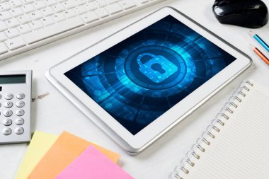 Ofis eşyalarıyla iş yeri ve ekranda asma kilit simgesi olan tablet
