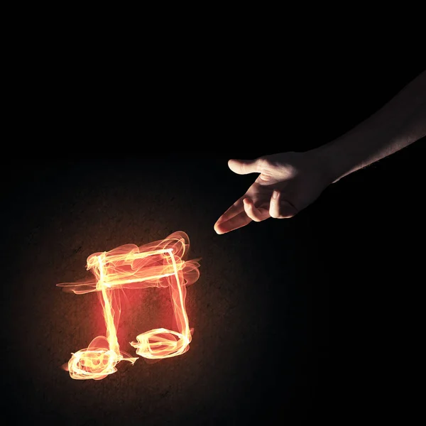 Close up of person hand and fire music symbol on dark background