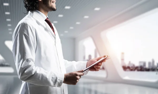 有信心的医生在白色不育大衣的形象站在白色医院办公楼内阳光明媚背景 — 图库照片