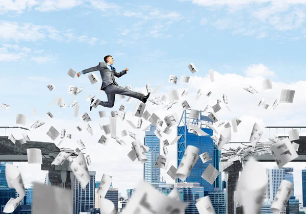 Geschäftsmann Springt Mit Fliegenden Papierdokumenten Über Eine Betonbrücke Als Symbol — Stockfoto