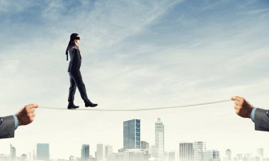 Gözlerinde perde olan bir iş adamı şehrin arka planında ipte yürüyor.