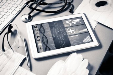 Gri yüzeyde beyaz tablet ve doktor araçları