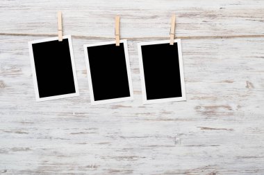 Boş fotoğraf çerçevesi ahşap bir zeminde ipte asılı.