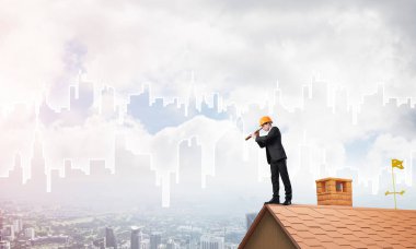 Takım elbiseli genç işadamı ve çatıda kask var. Karışık ortam