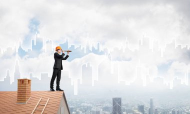 Takım elbiseli genç işadamı ve çatıda kask var. Karışık ortam