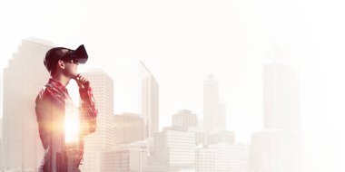 Sanal gerçeklik kulaklığı olan genç bir adam ya da şehrin arka planında 3 boyutlu gözlüklü.