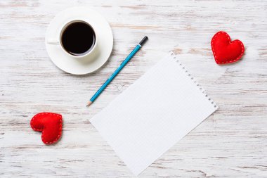 Kahve fincanı not defteri kalem ve ahşap yüzeyde iki kırmızı kalp