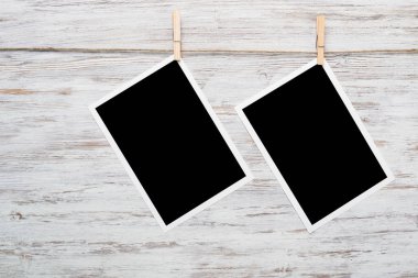 Boş fotoğraf çerçevesi ahşap bir zeminde ipte asılı.