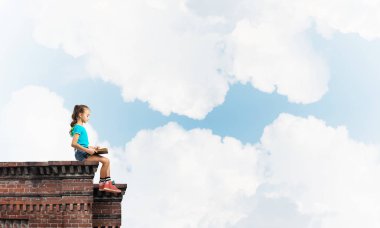 Çatı ve kitap okumak binasında oturan sevimli kız