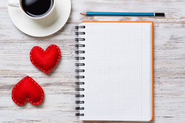 Kahve fincanı not defteri kalem ve ahşap yüzeyde iki kırmızı kalp