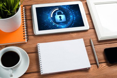 Ofis eşyalarıyla iş yeri ve ekranda asma kilit simgeleri olan tablet