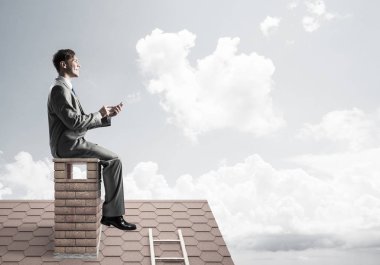 Elinde cep telefonu ile evin baca oturan genç işadamı