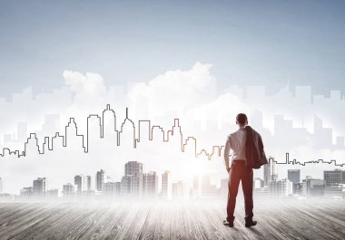 İşadamı arkasını dönüp modern iş merkezinin siluetine bakıyor.