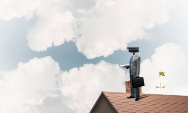 Evin çatısında baş durmak yerine kamerayla zum yapan yüzü olmayan bir iş adamı.