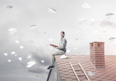 Elinde kırmızı kitap ile ev üzerinde oturan genç adam