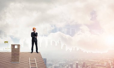 Takım elbiseli genç işadamı ve çatıda kask var. Karışık ortam