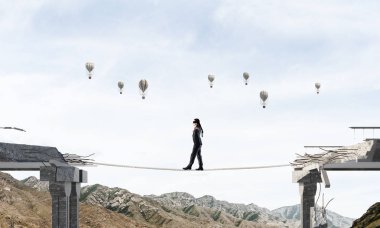 İş adamı, gizli tehditler ve risklerin sembolü olarak köprüdeki büyük boşluğun üzerinde gözleri bağlı bir iple yürüyor. Uçan balonlar ve arka planda doğa manzarası. 3B görüntüleme.