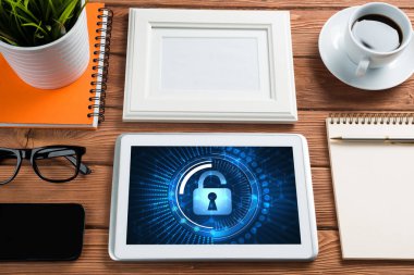 Ofis eşyalarıyla iş yeri ve ekranda asma kilit simgeleri olan tablet