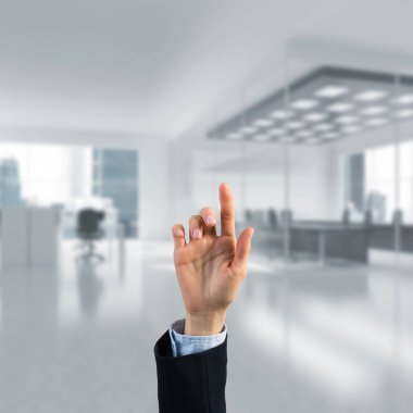 İş kadınının eli ekranda kapalı, arka planda parmak ve ofis var.