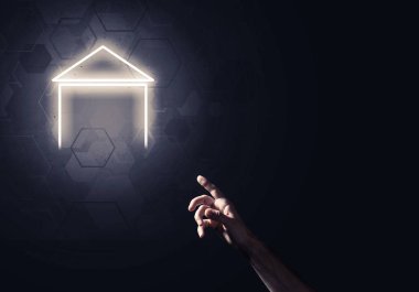 İnsanın eli parlayan ev simgesi ya da sembolüyle dokunuyor