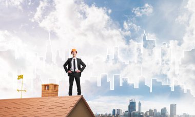 Takım elbiseli genç işadamı ve çatıda kask var. Karışık ortam