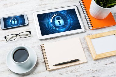 Ofis eşyalarıyla iş yeri ve ekranda asma kilit simgeleri olan tablet