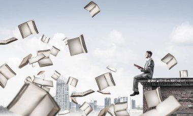 Elinde kırmızı kitap ile kenar binasında oturan genç işadamı