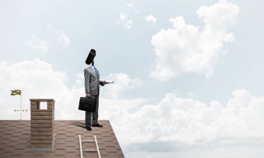 Evin çatısında baş durmak yerine kamerayla zum yapan yüzü olmayan bir iş adamı.