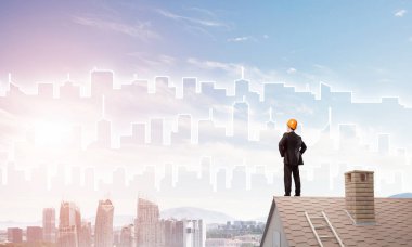 Takım elbiseli genç işadamı ve çatıda kask var. Karışık ortam