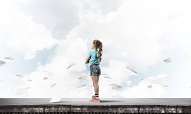 Sevimli kız etrafında uçan çatı ve kağıt uçaklar binasında ayakta