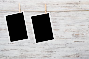 Boş fotoğraf çerçevesi ahşap bir zeminde ipte asılı.