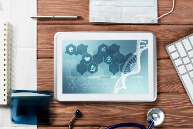 Beyaz tablet bilgisayar ve doktor aletleri ahşap masada.