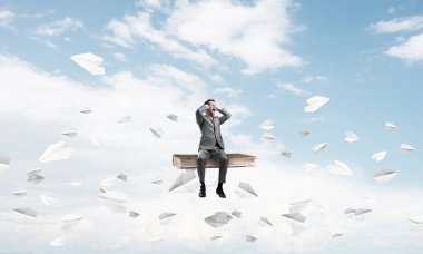 Eski kitap üzerinde oturan ve elleriyle kulaklarını kapatarak sinirli işadamı