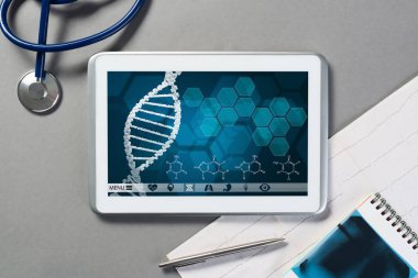 Gri yüzeyde beyaz tablet ve doktor araçları