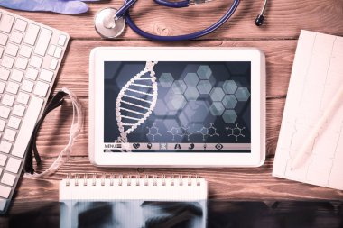 Beyaz tablet bilgisayar ve doktor aletleri ahşap masada.