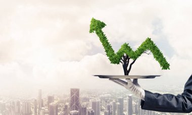 Garson kızın elinde beyaz eldiven ile cityscape arka plan üzerinde metal tepsi üzerinde yeşil büyüyen grafik sunma kırpılmış görüntü.