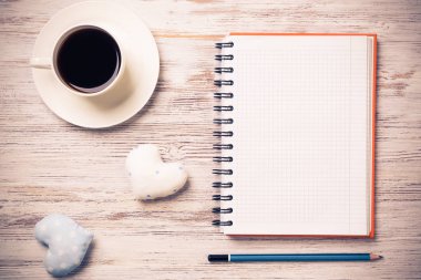 Kahve fincanı not defteri kalem ve ahşap yüzeyde iki kalp