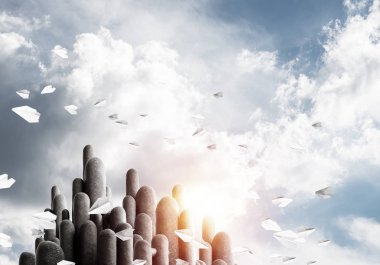 Açık havada, arka planda güzel manzarası olan uçan kağıt uçaklar arasında yer alan yüksek ve büyük taş sütunların resmi. Duvar kağıdı, telif alanı olan arkaplan.