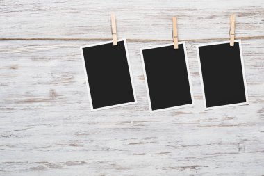 Boş fotoğraf çerçevesi ahşap bir zeminde ipte asılı.