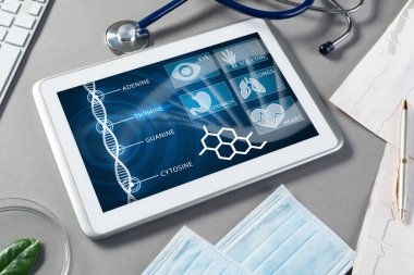 Gri yüzeyde beyaz tablet ve doktor araçları