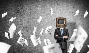 İşadamı kıyafetli kafa duran kağıtları uçan arasında geçti silah tutmak yerine eski Tv ve arka plan üzerinde koyu gri Duvar ile.