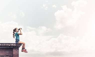 Dürbünle bakan, okul çağındaki sevimli kız çatıyı inşa ediyor.