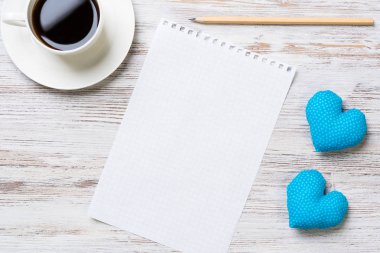 Kahve fincanı not defteri kalem ve ahşap yüzeyde iki kalp