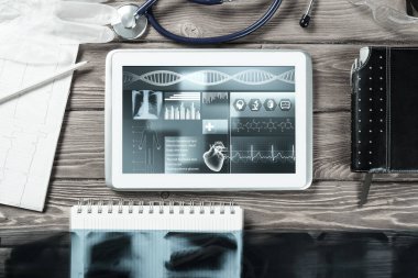Beyaz tablet bilgisayar ve doktor aletleri ahşap masada.