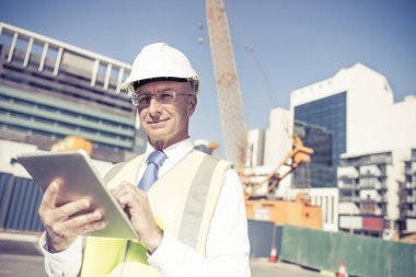 Kıdemli mühendis erkek takım elbise ve tablet PC'de çalışma kask