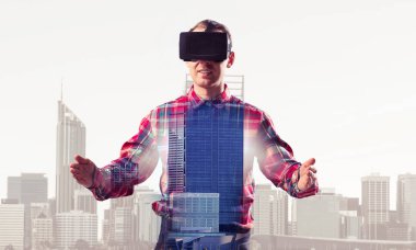 Sanal gerçeklik kulaklığı olan genç bir adam ya da şehrin arka planında 3 boyutlu gözlüklü.